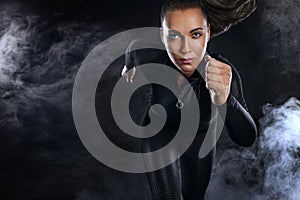 Strong athletic woman sprinter, running on black background wearing in the sportswear. Fitness and sport motivation