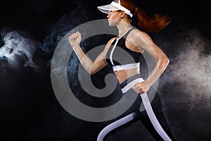 Strong athletic woman sprinter, running on black background wearing in sportswear. Fitness and sport motivation. Run