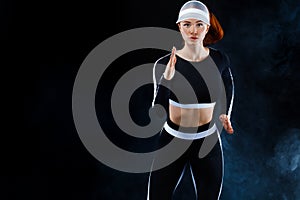 Strong athletic woman sprinter, running on black background wearing in sportswear. Fitness and sport motivation. Run