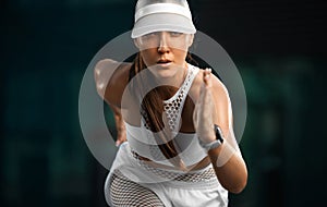 Strong athletic woman sprinter running in the city wearing white sportswear. Fitness and sport motivation outdoor in