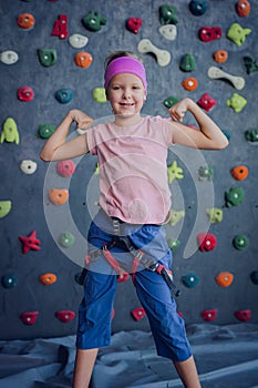 A strong baby climber posing for photographer at artificial wall.