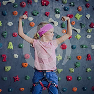 A strong baby climber posing for photographer at artificial wall.