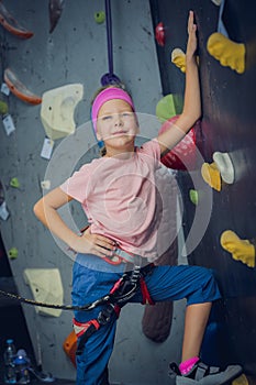 A strong baby climber posing for photographer at artificial wall.