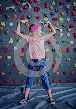 A strong baby climber posing for photographer at artificial wall.