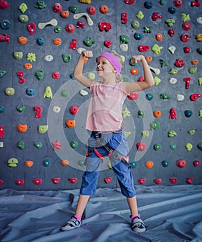 A strong baby climber posing for photographer at artificial wall.