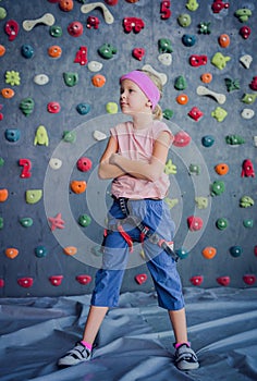 A strong baby climber posing for photographer at artificial wall.