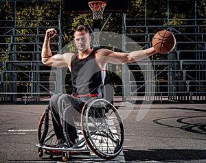 Strong basketball player in wheelchair pose with a ball on open gaming ground.