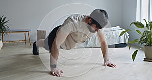 Strong bearded man doing push ups exercise at home