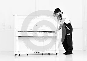 Strong bearded man moving old wooden piano with open keyboard isolated on white background. Handsome guy playing easy