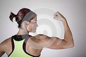 Strong Beautiful fitness woman flexing her arm and back muscles