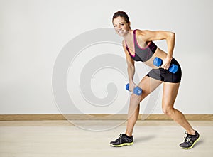 Strong Beautiful fitness woman lifting weights indoors