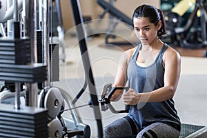 Strong and beautiful woman rowing at the cable machine during workout