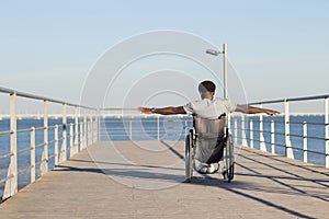 Strong Black man riding wheelchair at seafront photo