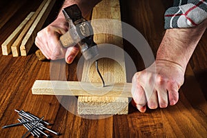 After a strong blow with a hammer, a nail was bent. Carpenter hands closeup. Working environment in carpentry workshop