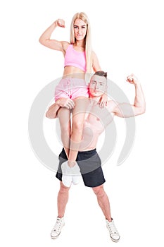 Strong bodybuilder man holding fitness woman on his shoulder