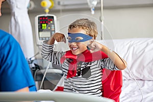 Strong boy in superhero costume at hospital