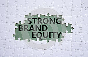 Strong Brand Equity symbol. Concept words Strong Brand Equity on white puzzle. Beautiful grey green background. Business and