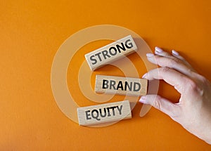 Strong Brand Equity symbol. Concept words Strong Brand Equity on wooden blocks. Businessman hand. Beautiful orange background.