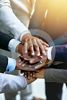 Strong business starts with a strong team. a group of businesspeople joining their hands in solidarity.