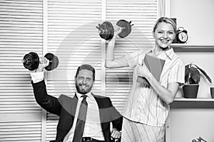 Strong business team. Healthy habits in office. Man and woman raise heavy dumbbells. Strong powerful business strategy