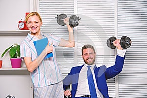 Strong business team. Healthy habits in office. Man and woman raise heavy dumbbells. Strong powerful business strategy