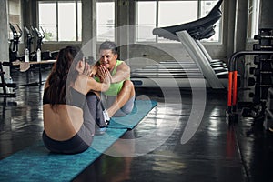 A strong Caucasian couple doing sit-ups exercise together at gym