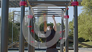 Strong Caucasian man working out on monkey bars in park.