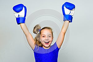 Strong child proud winner boxing competition. Girl child happy winner with boxing gloves posing on grey background. She