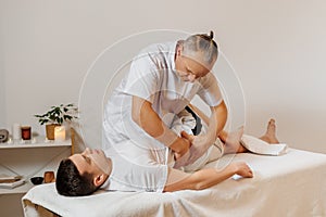 Strong and concentrated masseur therapist in uniform making manual therapy for athlete back. Professional massage