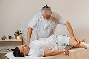 Strong and concentrated masseur therapist in uniform making manual therapy for sportsman. Professional massage back