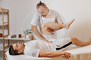 Strong and concentrated masseur therapist in uniform making manual therapy for sportsman. Professional massage back
