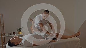 Strong and concentrated masseur therapist in uniform making manual therapy for sportsman. Professional massage back