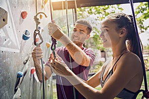 A strong couple of climbers climb an artificial wall with colorful grips and ropes.