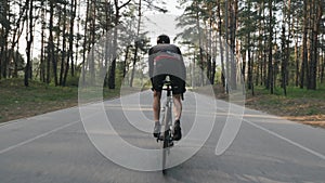 Strong cyclist riding a bicycle out of the saddle. Cyclist with strong leg muscles pedaling. Back follow shot. Cycling concept. Sl