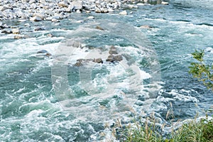 Strong and danger cold flowing blue river water and huge stone a