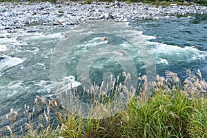 Strong and danger cold flowing blue river water and huge stone a