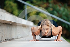 Blonde woman doing push ups outdoor.