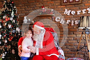 Strong embrace between happy female child of girl and Santa Cla