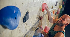 Strong Experienced Rock Climber Practicing Solo Climbing on Bouldering Wall in Gym. Man Exercising