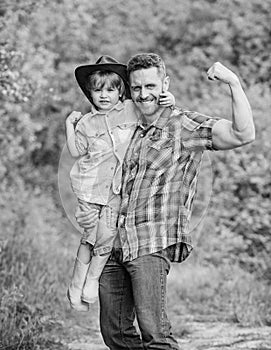 Strong father and son in cowboy hat on ranch. kid in rubber boots. happy man dad in forest. human and nature. family day