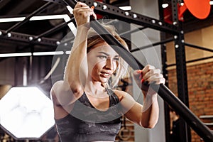 Strong female athlete looking down and holding the hammer in the sport center.