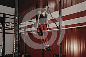 Strong female athlete practicing calisthenics, doing ring dips