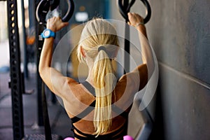 Strong female doing exercises with fitness gymnastics straps in gym