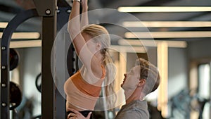 Strong fit girl making pullups at gym. Male trainer controlling woman client