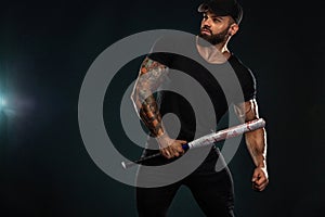 Strong and fit man bodybuilder with baseball bat in black t-shirt. Sporty muscular guy athlete. Sport and fitness