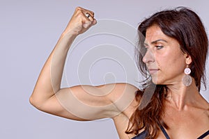 Strong fit mature woman flexing her arm muscles photo