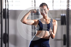 Strong, fit and thumbs up sign of a successful woman in a healthy muscular body at a gym. Portrait of a happy, smiling