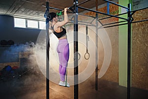 Strong fit woman doing pull up on horizontal bar.