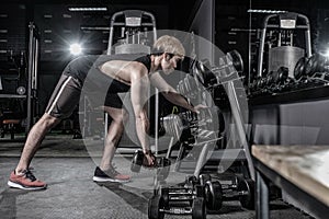 Strong fitness man doing arm workout with dumbbell in the gym