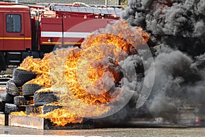 Strong flames from burning car tires on background of a fire truck. firefighters training